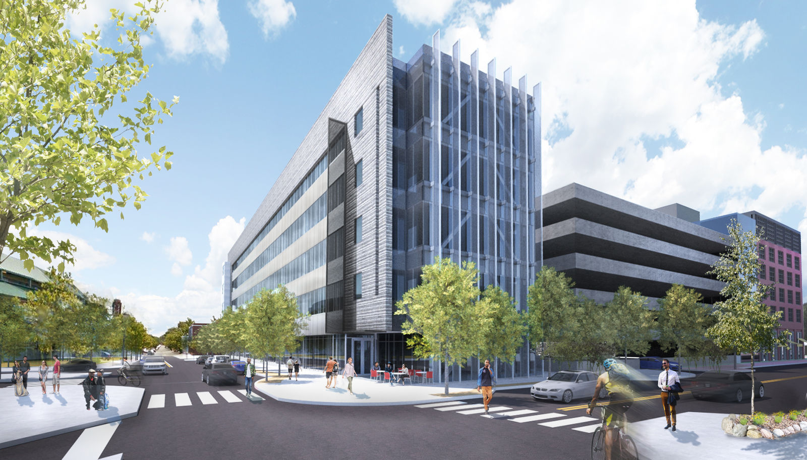 A modern glass and metal building with vertical fins on its facade sits at a Philadelphia street corner. People walk, bike, and enjoy outdoor tables among green trees, as cars and a parking garage frame this vibrant, educational hub.