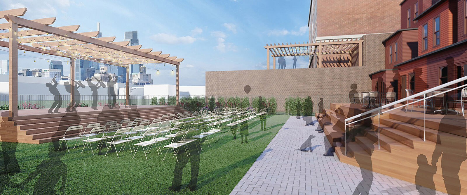 Outdoor event space in Philadelphia with a wooden stage, rows of white chairs on the grass, people milling around, and a pergola overhead. The setting blends educational charm with city views, reflecting the area’s commitment to historic preservation.