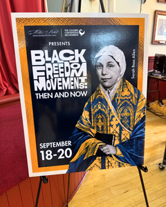 Poster on easel titled Black Freedom Movements: Then and Now with dates September 18-20, featuring an image of Sarah Bass Allen in ornate historic clothing. Event sponsors logos appear at the top.